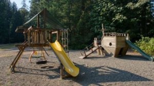 Image of a playground featuring a slide, tire swing, rope ladder, and playable arc